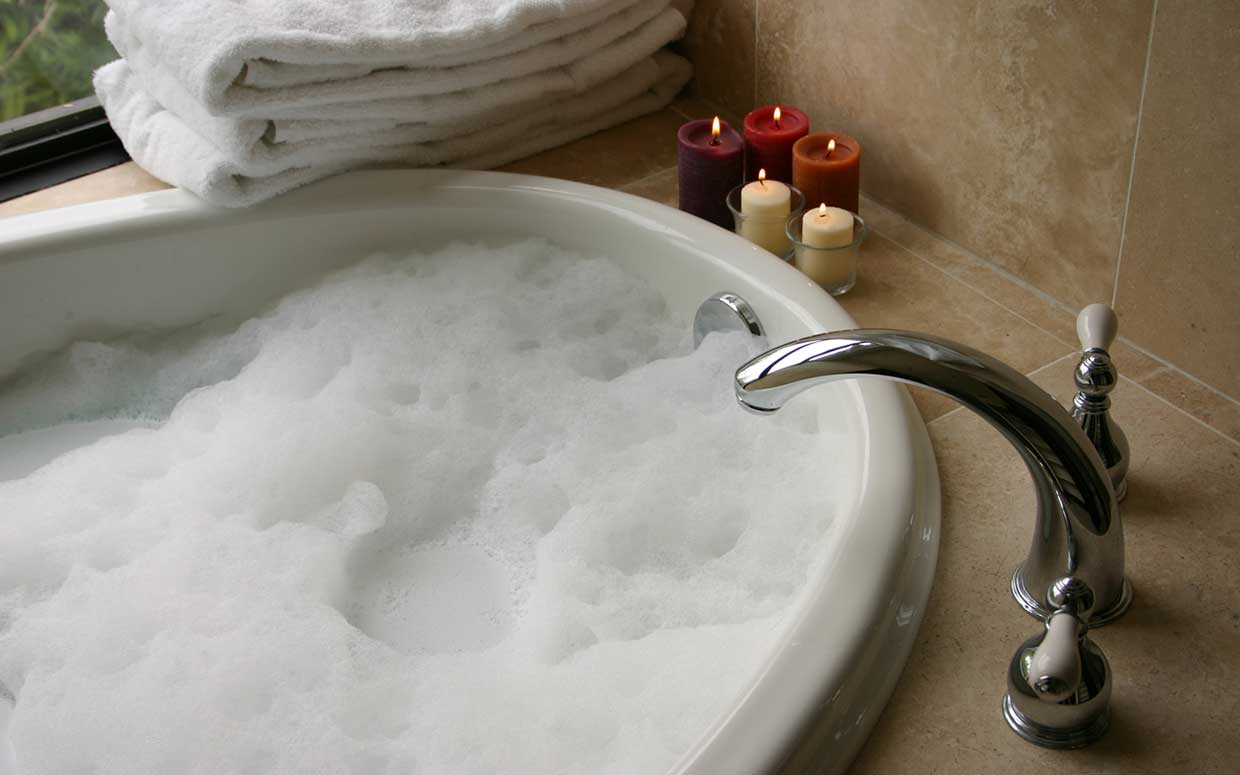 A bubble bath with lit candles beside it